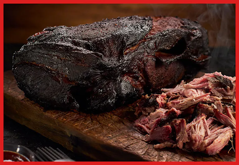 A smoked, whole brisket rests on a rustic wooden board, alongside tender pulled beef, releasing smoky steam.