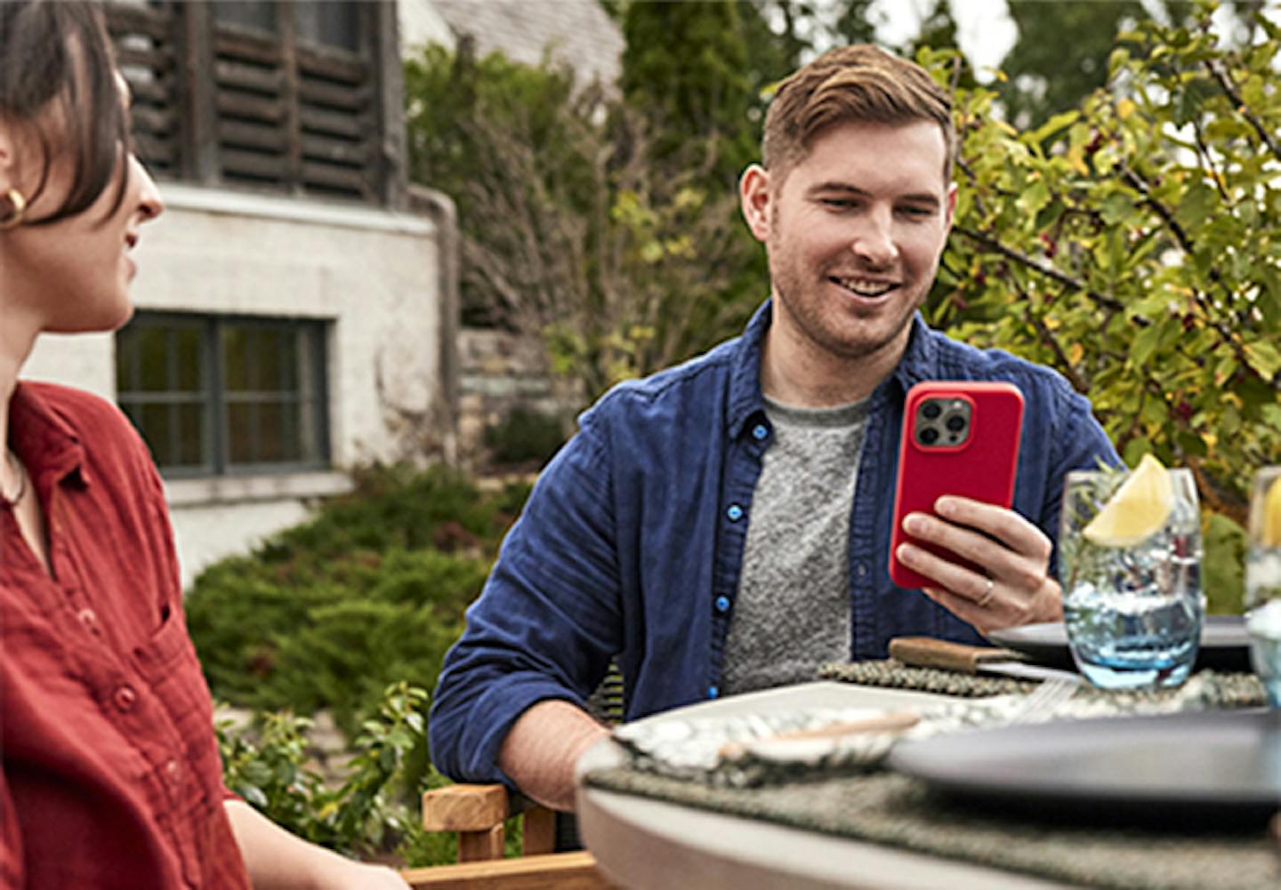 Two people sitting outside with one person checking a smartphone