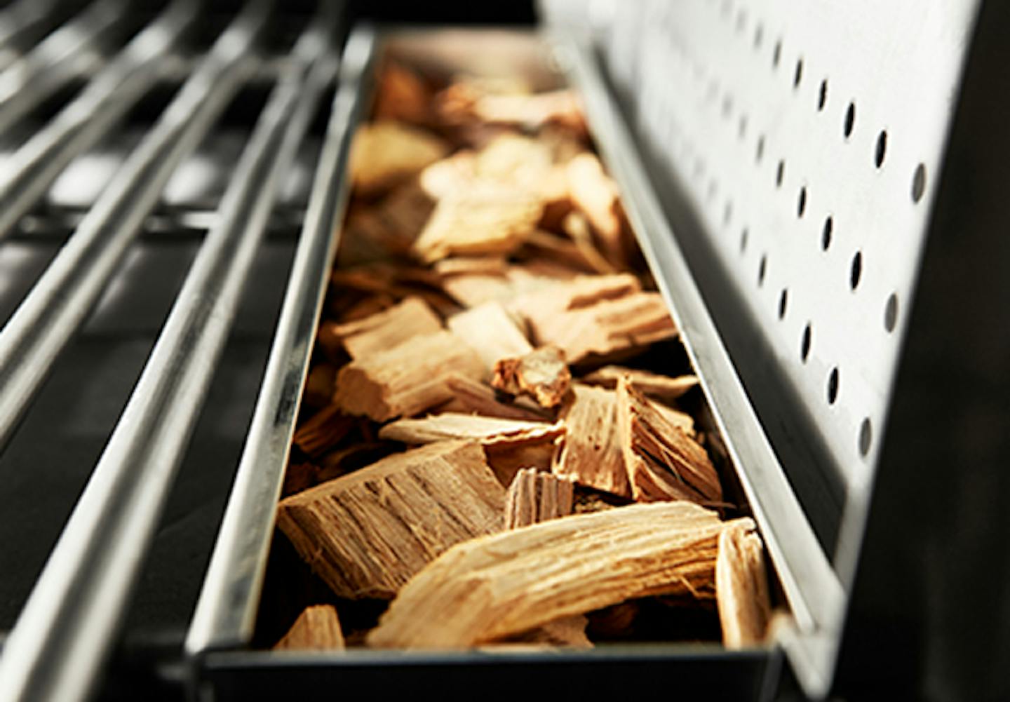 An open smoker box with wood chips