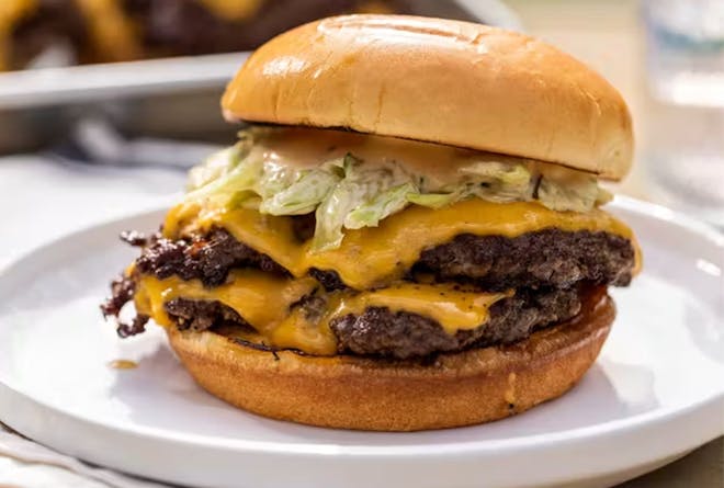 Double smashed cheeseburger on a white plate