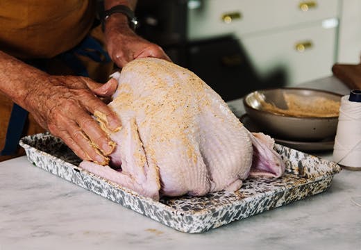 spreading butter with herbs and spices on turkey