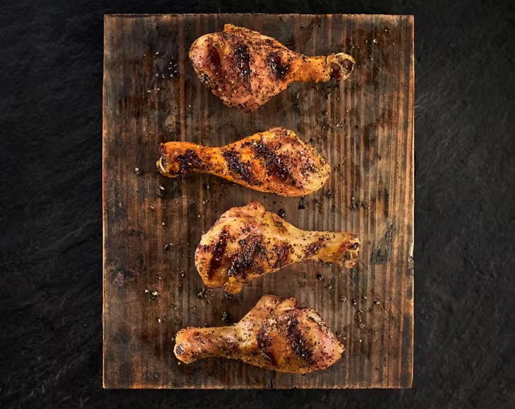 Grilled Chicken drumsticks with grill marks on a wood board